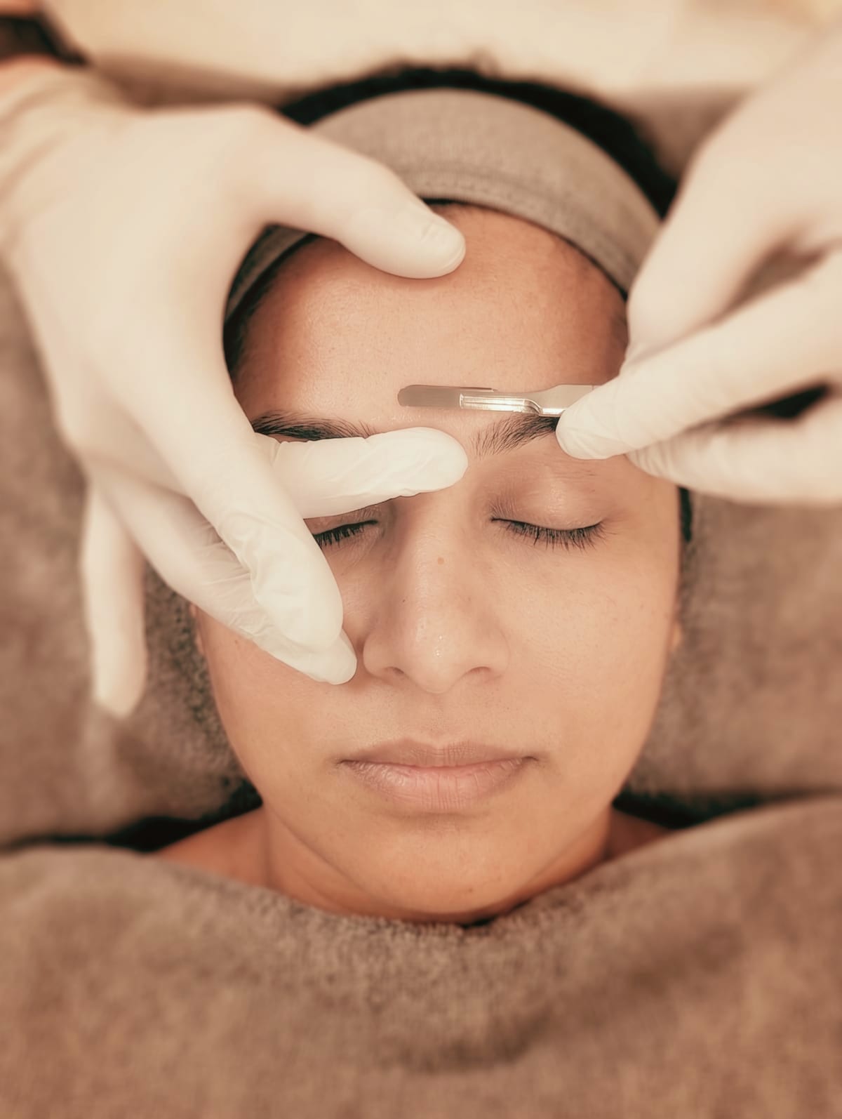 Close-up of a dermaplaning treatment with a scalpel along the brow area