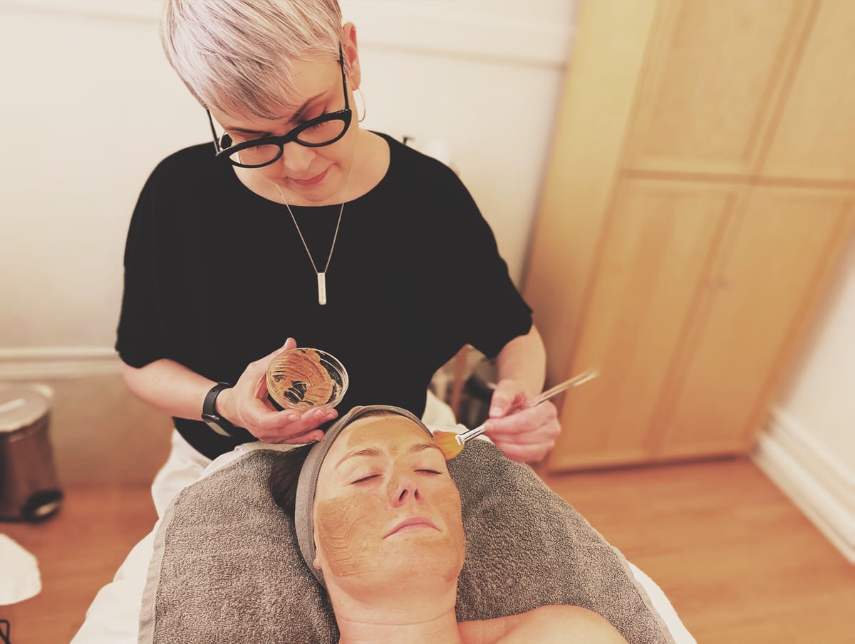 Jill Jodar applying a custom-blended mask with a fan brush during a facial treatment